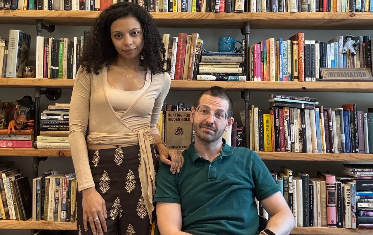 Tara Pacheco and Alexander Katz in front of floor-to-ceiling bookshelves